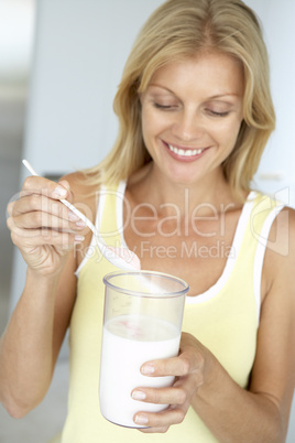 Blonde Frau hält ein großes Glas Milch in der Hand