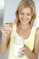 Blonde Frau hält ein großes Glas Milch in der Hand