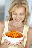 Blonde Frau hält eine Schale mit Karottensticks