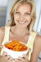 Blonde Frau hält eine Schale mit Karottensticks