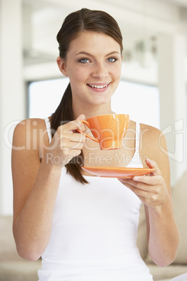 Eine junge Frau hält eine orange Kaffeetasse