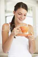 Eine junge Frau hält eine orange Kaffeetasse