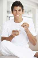 Junger Mann hält einen Joghurt in der Hand