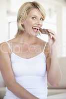 Blonde Frau hält eine Tafel Schokolade in der Hand