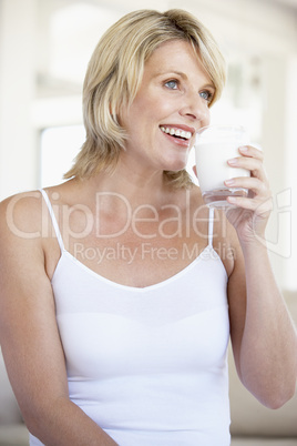 Eine junge blonde Frau hält ein großes Glas Milch