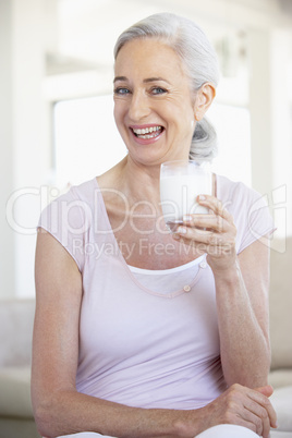 Frau mit langen grauen Haaren hält ein Glas Milch