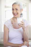 Frau mit langen grauen Haaren hält ein Glas Milch
