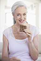 Frau mit weissen Haaren hält eine Tafel Schokolade