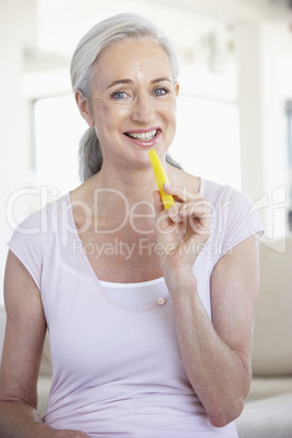 Frau mit weissen Haaren hält einen gelben Paprika