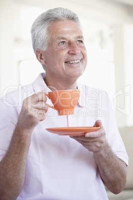 Ein Mann hält eine orange Tasse mit Unterteller