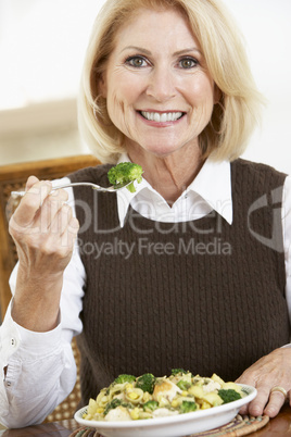 Eine Dame sitzt vor einem Gemüseteller mit Nudeln