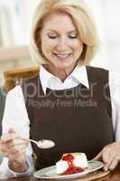 Eine blonde Frau isst ein Stück Kuchen