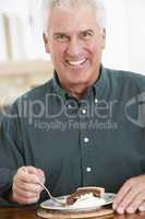 Mann mit grauen Haaren isst ein Stück Kuchen