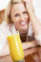 Blonde Frau sitzt hinter einem Glas Orangensaft
