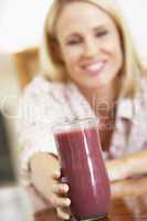 Blonde Frau hält ein Glas mit roten Obstsaft