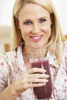 Blonde Frau hält ein Glas mit roten Obstsaft