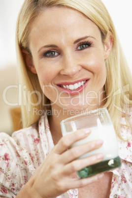 Blonde Frau hält ein großes Glas Milch in der Hand