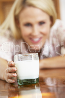 Blonde Frau hält ein großes Glas Milch in der Hand