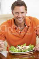 Gut aussehender Mann isst einen Teller Salat