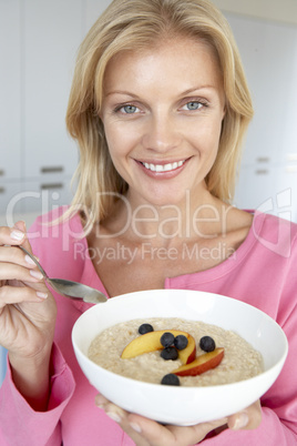 Eine blonde Frau mit Schale Brei und Früchten