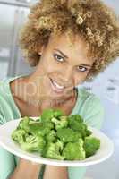 Eine dunkelhäutiger Frau hält einen Teller Brokoli