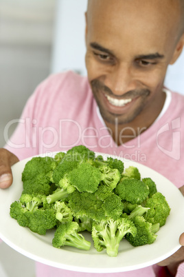 Dunkelhäutiger Mann hält einen Teller Brokoli