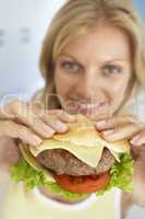 Blonde Frau hält einen Hamburger hoch