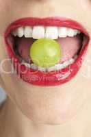 Roter Mund mit Weintraube zwischen den Zähnen