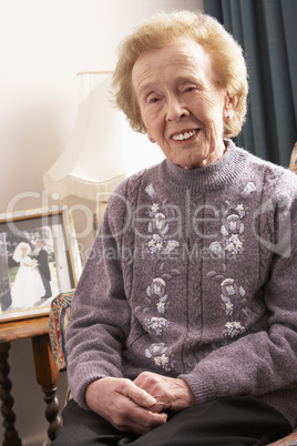 Alte Frau in lila Pullover sitzt im Wohnzimmer