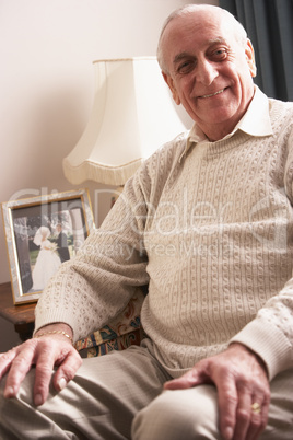 Älterer Herr sitzt im Wohnzimmer und lächelt