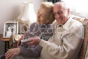Altes Ehepaar sitzt eng nebeneinander und fernsehen