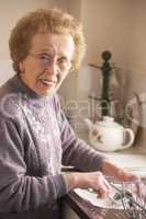Ältere Frau mit Brille beim Abwasch