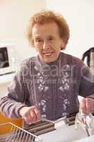 Senorin in lila Pullover macht den Abwasch