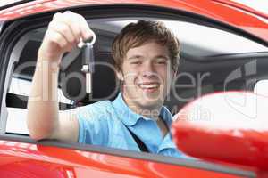 Junger Mann hält freudig den Autoschlüssel