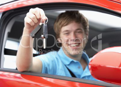 Junger Mann hält freudig den Autoschlüssel