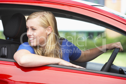 Junge blonde Frau fährt rückwärts in einem roten Auto