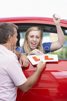 Junge Frau sitzt im roten Auto und jubelt