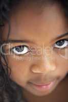 Kleines Mädchen mit großen Augen und dunkler Haut