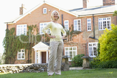 Eine Frau steht im Garten mit Haus im Hintergrund