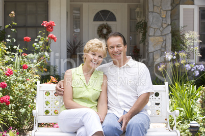 Glückliches Ehepaar sitzt auf der Bank vor dem Haus