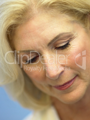 Schöne blonde Frau mittleren Alters mit Blick nach unten