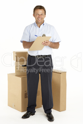 Portrait Of Courier Standing Next To Parcels, Holding A Clipboar