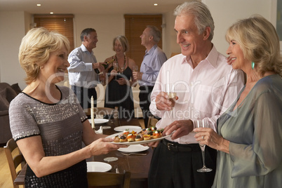 Woman Serving Hors D'oeuvres To Her Guests At A Dinner Party