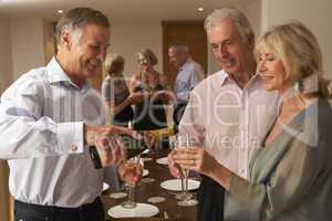 Man Serving Champagne To His Guests At A Dinner Party