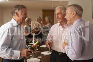 Man Serving Champagne To His Guests At A Dinner Party