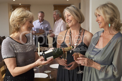 Woman Serving Champagne To Her Guests At A Dinner Party