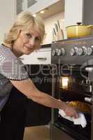 Woman Taking Food Out Of The Oven