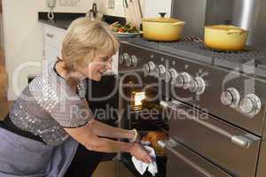 Woman Taking Food Out Of The Oven