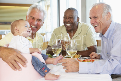 Man Showing His Baby Granddaughter To Friends At A Restaurant