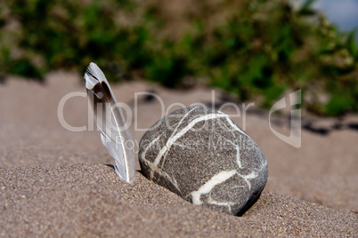 Steine und Feder im Sand